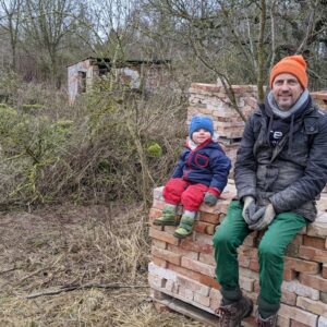 Vater und Kind sitzen auf gestapelten Ziegelsteinen während Bauprojekt
