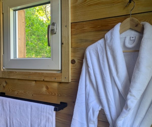 Flauschiger Bademantel und Handtuch in Jurte mit Holzwänden und Naturfenster