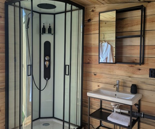 Modernes Badezimmer mit Eckdusche und Holzwand in exklusiver Jurte Seenplatte