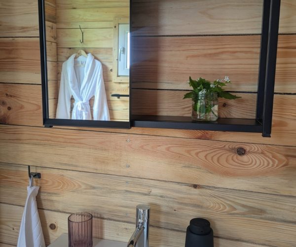 Waschbecken mit Spiegel und Holzwand im Badezimmer der Jurte Mecklenburgische Seenplatte