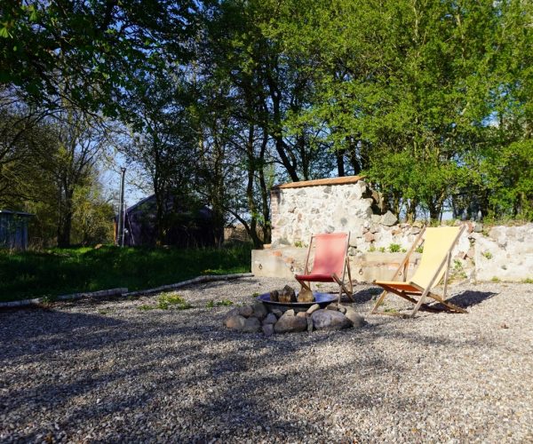 Feuerstelle mit Liegestühlen vor alter Steinmauer in der Mecklenburgischen Seenplatte