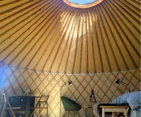 Jurte Innenraum mit rundem Dachfenster und Lichteinfall durch Holzstreben