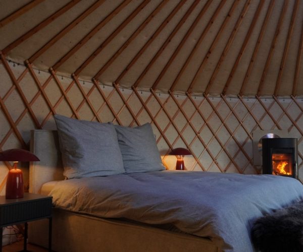 Schlafbereich Jurte mit Kaminofen und warmem Licht – Naturnaher Urlaub Seenplatte