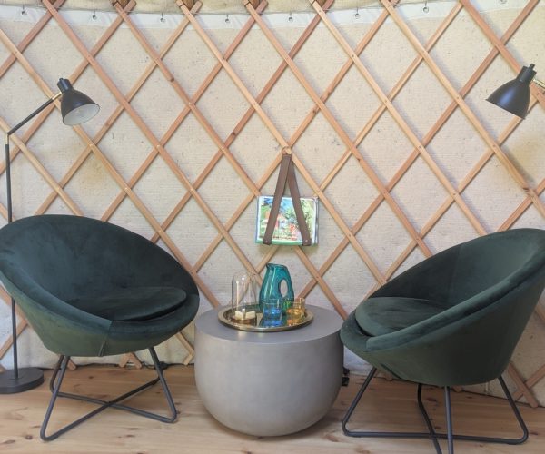 Zwei grüne Samtsessel mit rundem Tisch in Jurte mit Holzgitter-Wand