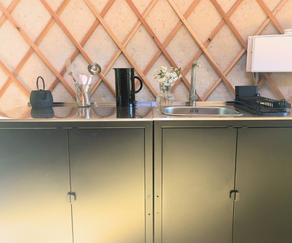 Moderne Küchenzeile mit Edelstahlspüle in Jurte mit Holzgitter-Wand